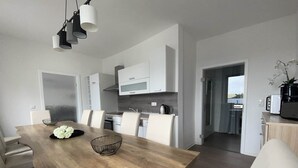 Una cocina moderna con armarios blancos, una mesa de comedor de madera y vistas al exterior.