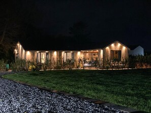A modern house with a well-lit exterior, a paved driveway, and a grassy lawn. - Private Lodge With Hot tub in Blackpool (Blackpool)