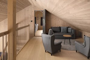 A wooden interior with a sofa, armchairs, and a small table.