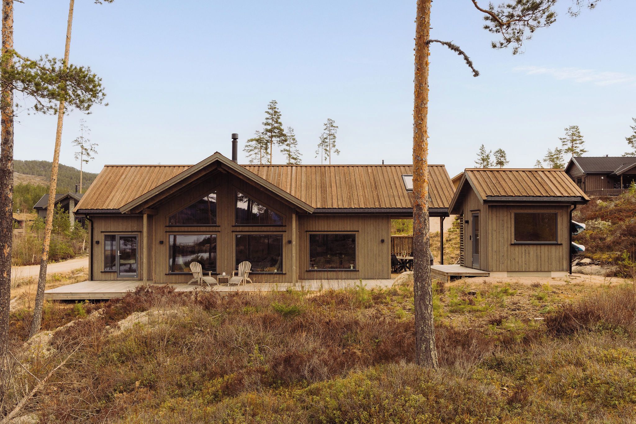 A wooden cabin with a large front window and a deck area.