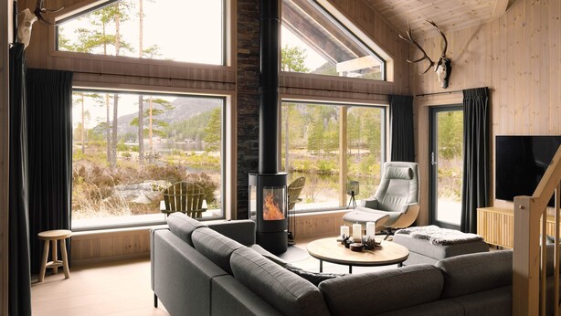 Una sala de estar moderna con chimenea, ventanas amplias y vistas al exterior.