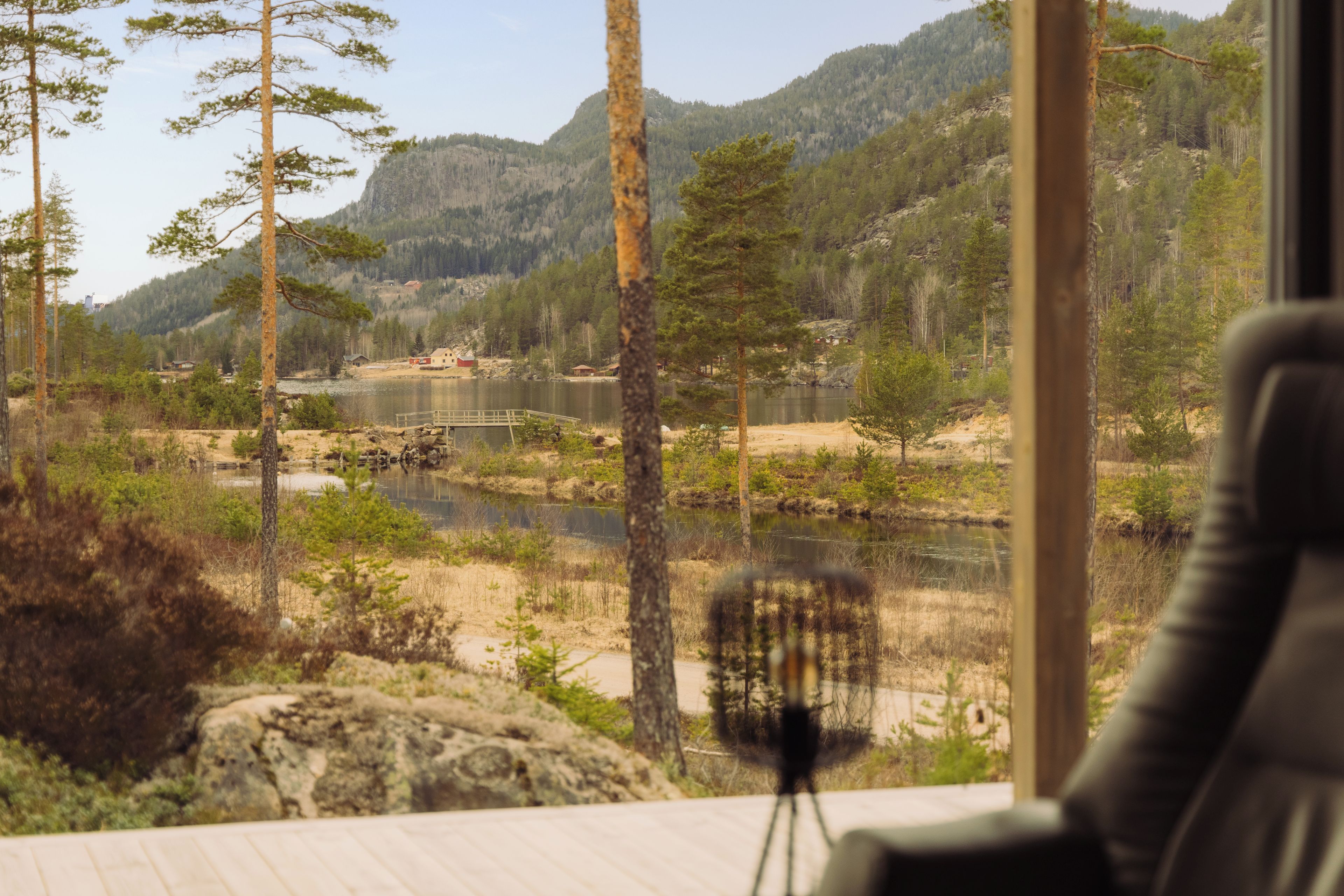 Ein Zimmer mit Blick auf einen See, umgeben von Bäumen und Bergen.