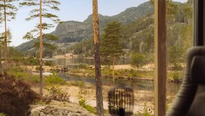 Una habitación con un amplio ventanal que da a un paisaje natural con árboles y un río.