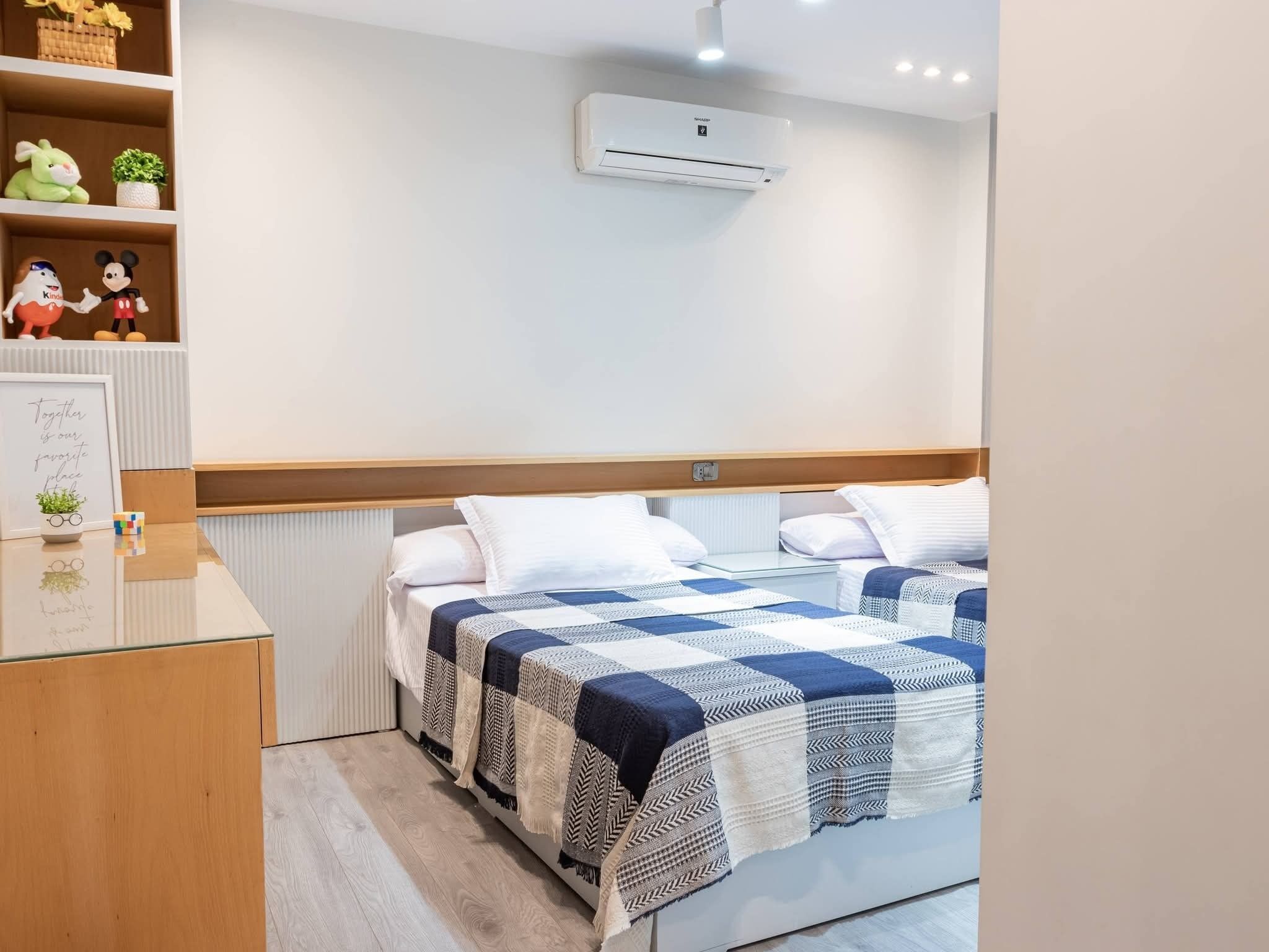 A bedroom with a bed, a bedside table, a shelf with decorative items, and an air conditioning unit.