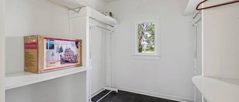 A room with white walls, a window with a view, a white shelf, and a cardboard box.