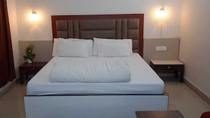A hotel room with a large bed, two bedside tables, a nightstand, and a small table. - Hotel City Palace (Ranchi)