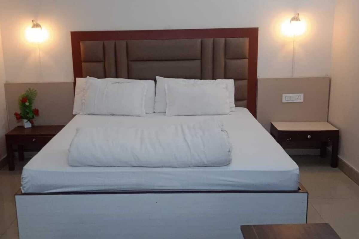 Una habitación de hotel con una cama grande, dos mesitas de noche y una pequeña mesa.