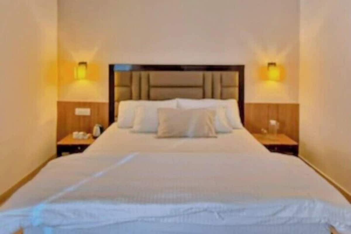 Una habitación de hotel con una cama grande, dos mesitas de noche y lámparas de pared.