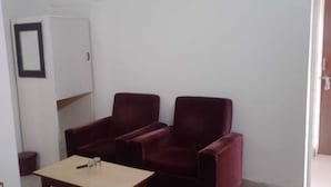 A room with two red armchairs, a small table with a glass, and a white cabinet. - Hotel City Palace (Ranchi)