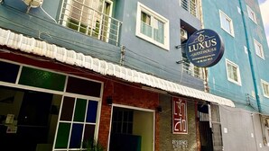 Een meerhoog gebouw met een bordje voor 'LUXUS GUESTHOUSE' en een zichtbare ingang.