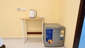 Een kitchenette met een koffiezetapparaat, een glas en een koelkast met een sticker voor 5 jaar garantie.