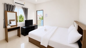 Una habitación de hotel con cama, televisor, escritorio y ventana con cortinas.