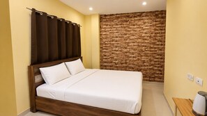 Una cama bien hecha en una habitación con pared de ladrillo y cabecera de madera.