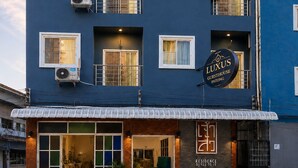 Een meerhoog gebouw met balkons, airconditioners en een bord met 'LUXUS GUESTHOUSE PATONG'.