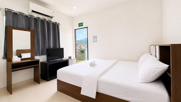 Een hotelkamer met een bed, een bureau, een televisie, een spiegel en een raam met uitzicht.