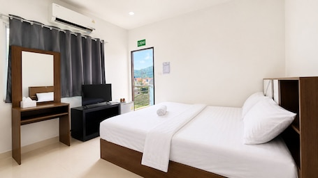 A hotel room with a bed, a desk, a TV, a mirror, and a window with a view.