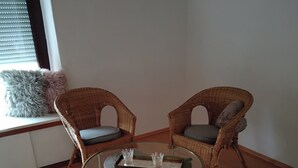 A room with two wicker chairs, a glass coffee table, and a round rug. - Cozy vacation apartment in Herdorf (Herdorf)
