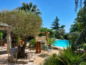 A pool area with a wooden deck, lounge chairs, and a pergola. - Villa Jardin Azur - Pool - Gulf of St-Tropez (Roquebrune-sur-Argens)