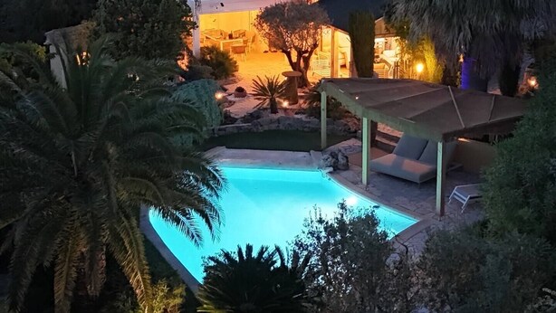 A large house with a swimming pool, surrounded by trees and a covered patio area.