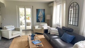 A living room with a sofa, armchairs, a coffee table, and a painting on the wall.