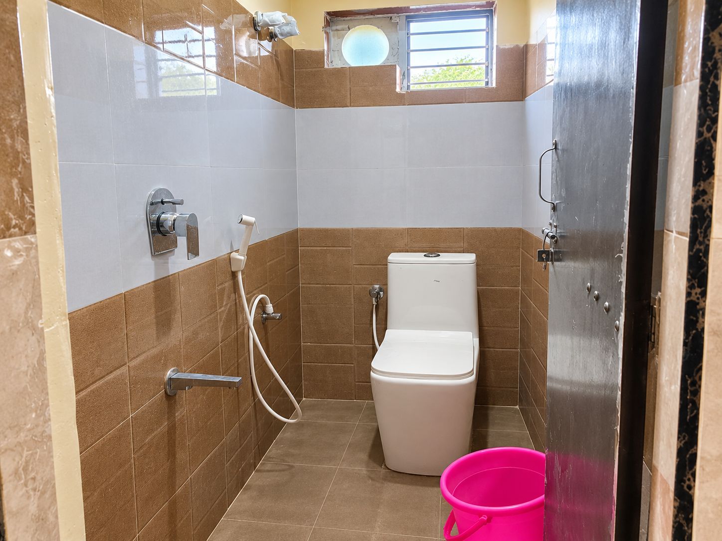 A small bathroom with a toilet, a shower, and a bucket.