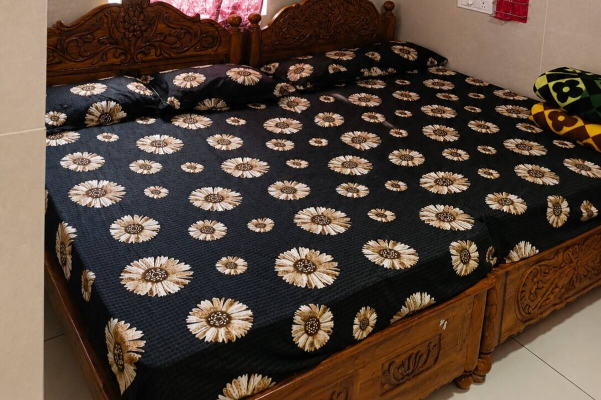 Quarto com cama, ar-condicionado, ventoinha no teto, janela com cortinas e tomada na parede.