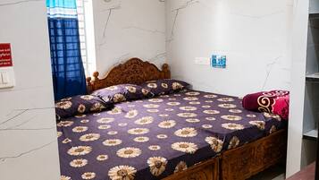 Quarto com cama, ventoinha no teto, janela com cortinas e ar-condicionado fixado na parede.