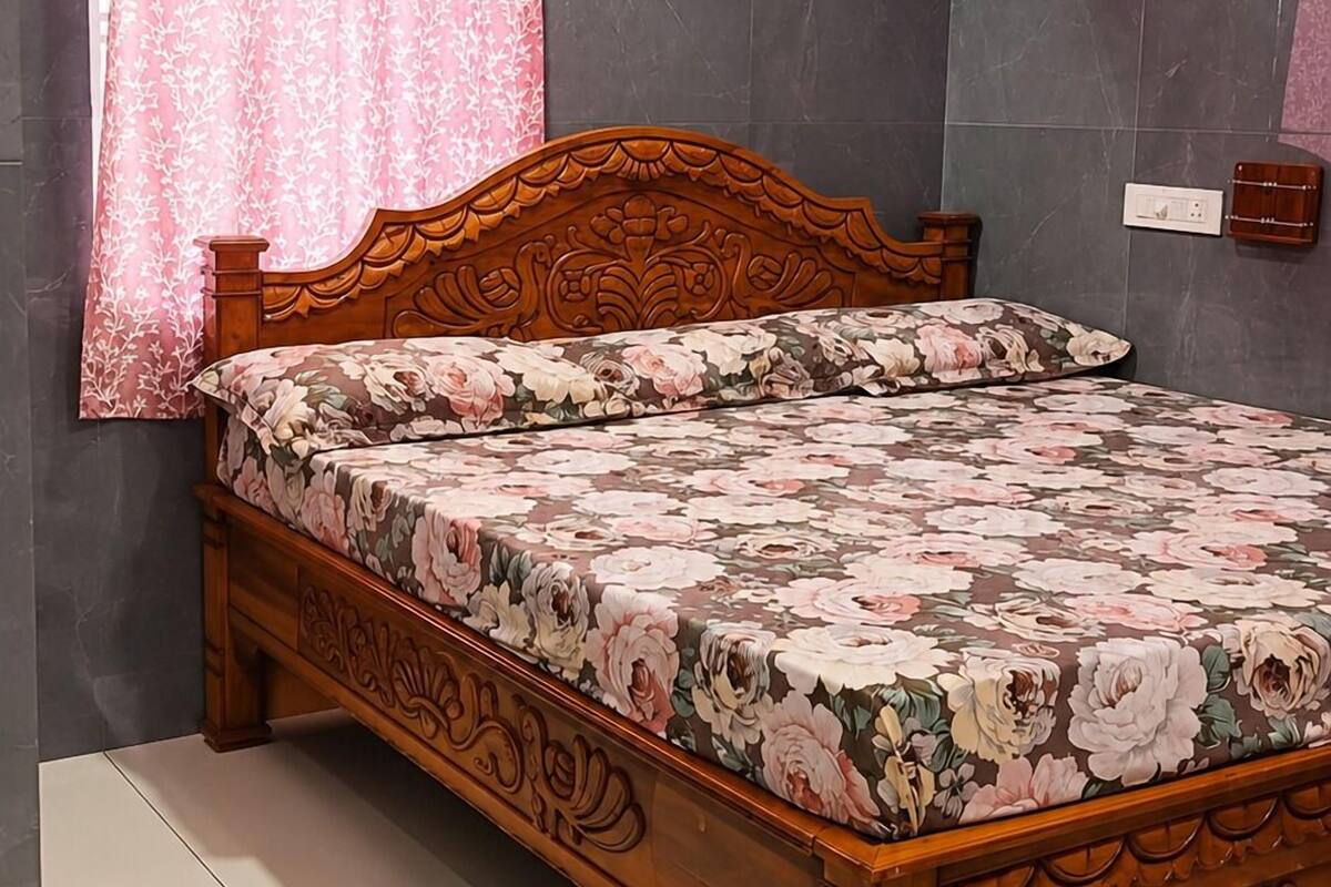 Quarto com cama de madeira, paredes cor-de-rosa, ventilador de teto e aparelho de ar condicionado.