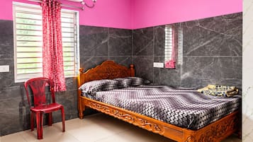 Een slaapkamer met een bed, een stoel, een raam met gordijnen en een airconditioning.