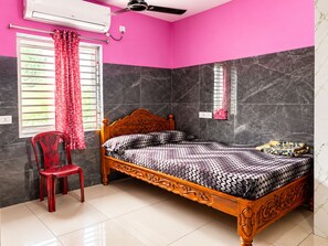 Un dormitorio con cama, una silla, un ventanal con cortinas e instalación de aire acondicionado.