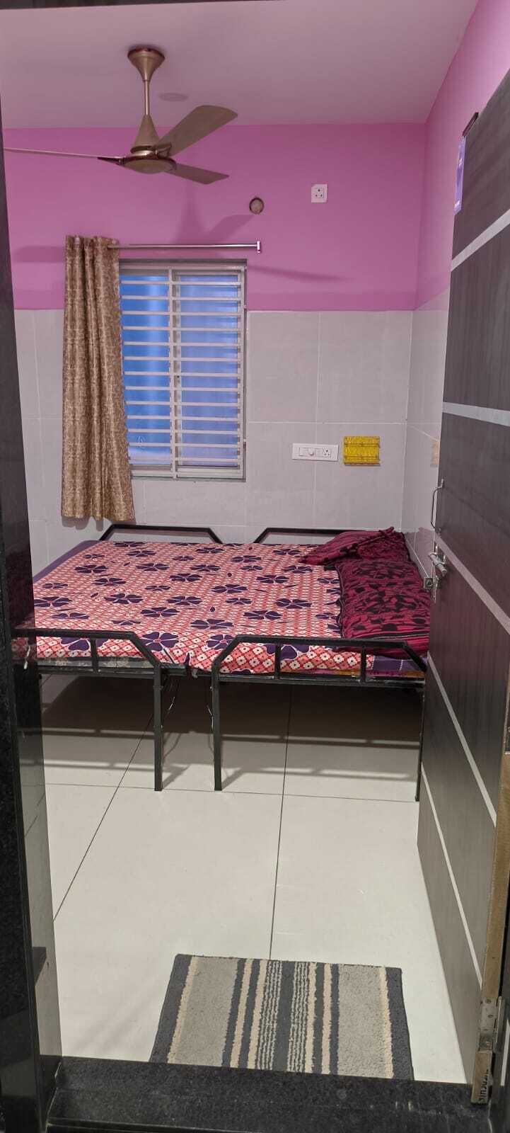 A room with a bed, a ceiling fan, a window with curtains, and a tiled floor.