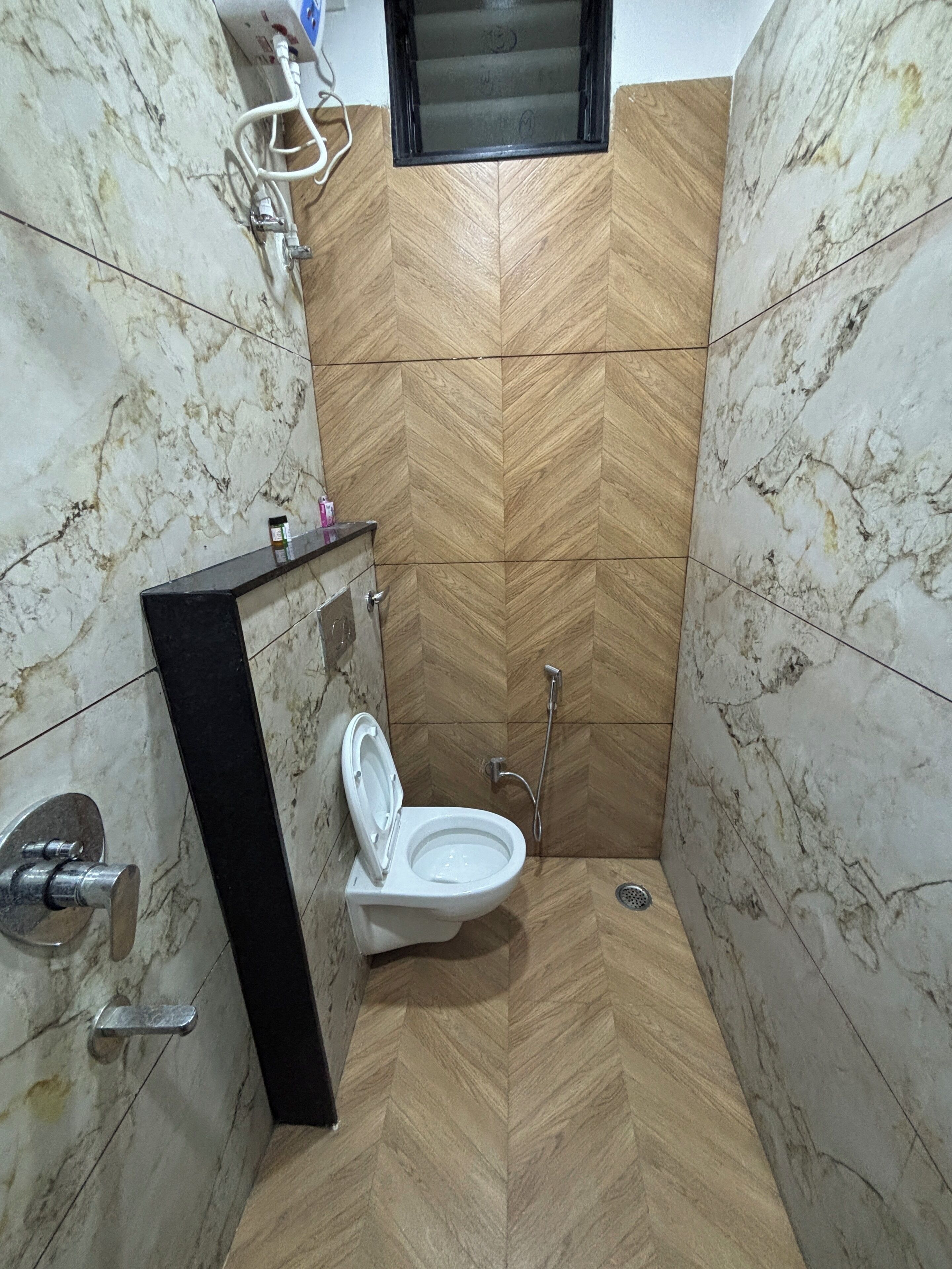 A bathroom with a white toilet, a wooden herringbone-patterned wall, and a black sink.