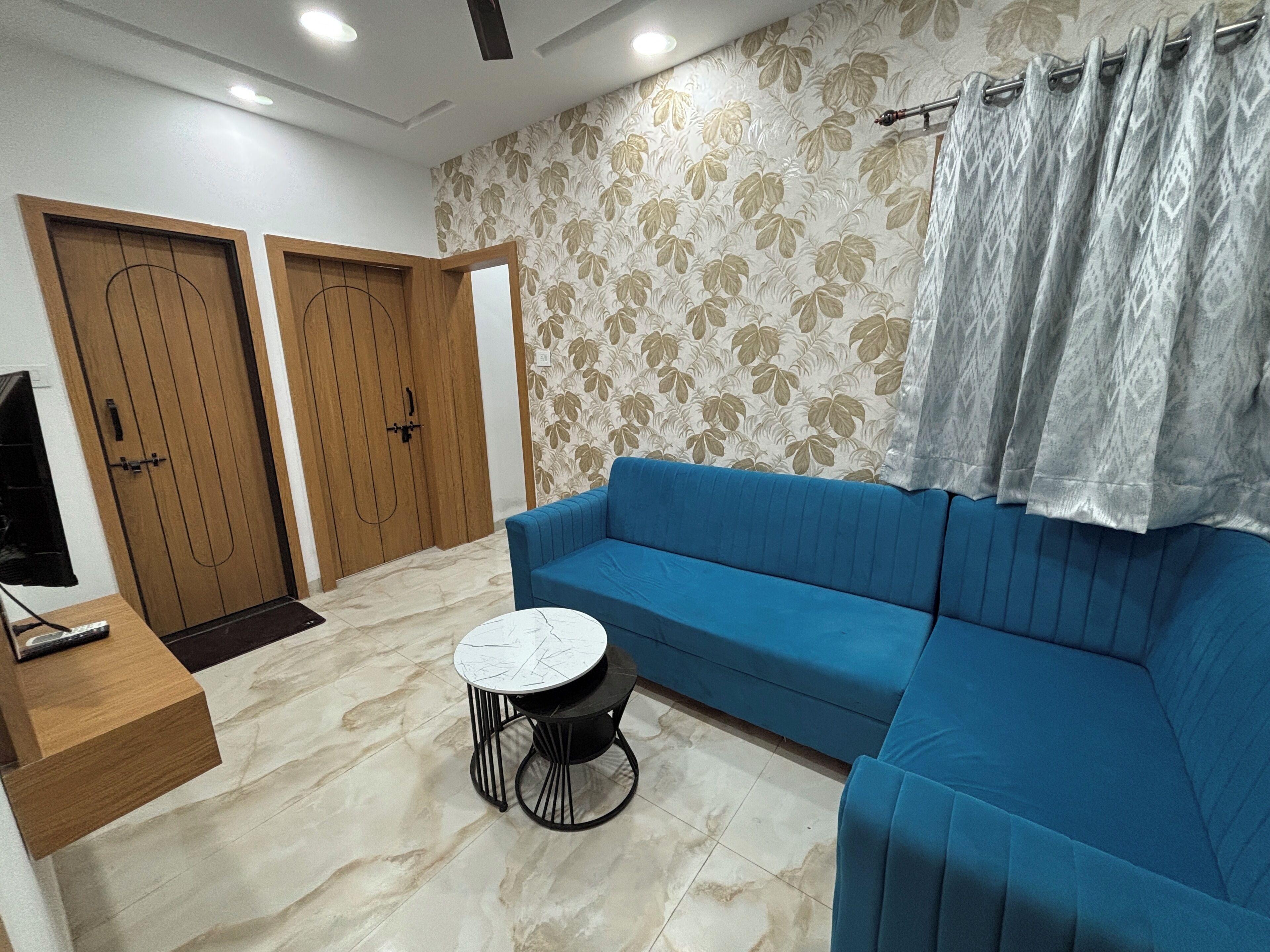 A room with a blue sofa, a small round table, and two wooden doors.