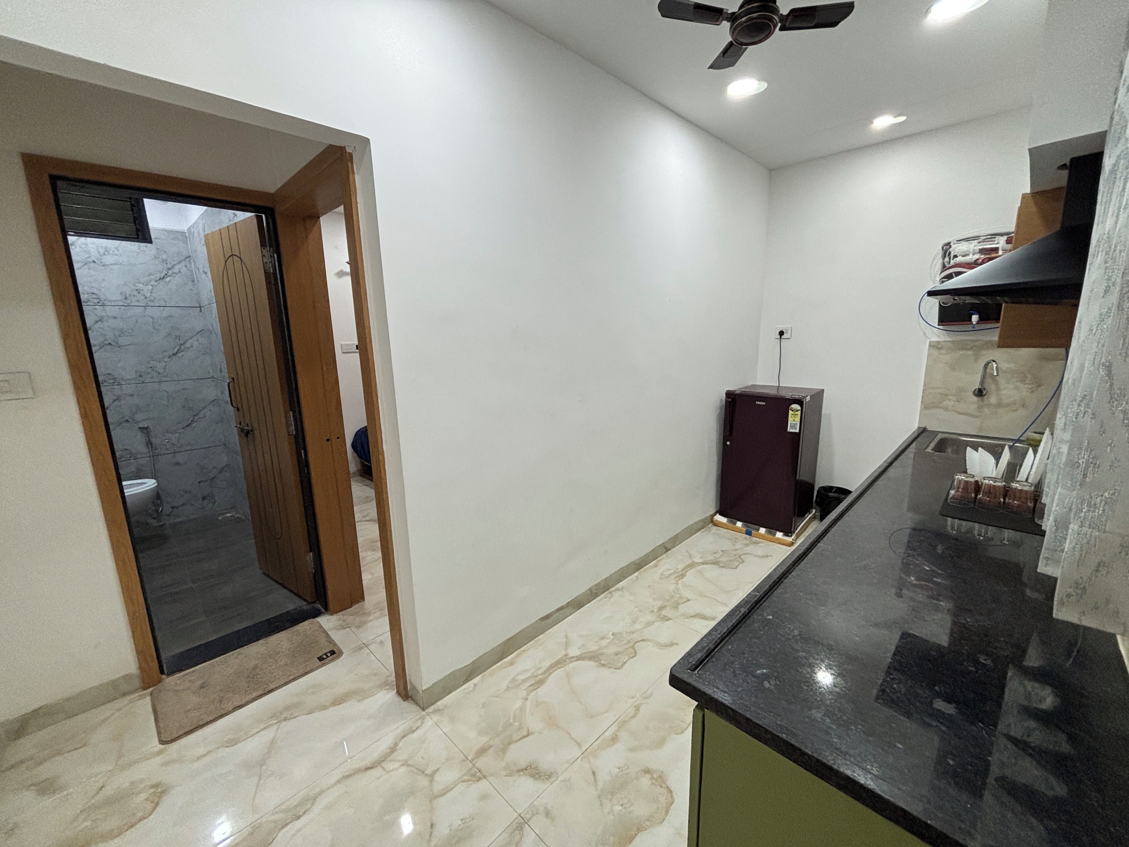 Una cocina con suelo de mármol, un refrigerador y un ventilador de techo.