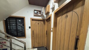 Un escalier menant à une porte en bois surmontée d’une fenêtre.