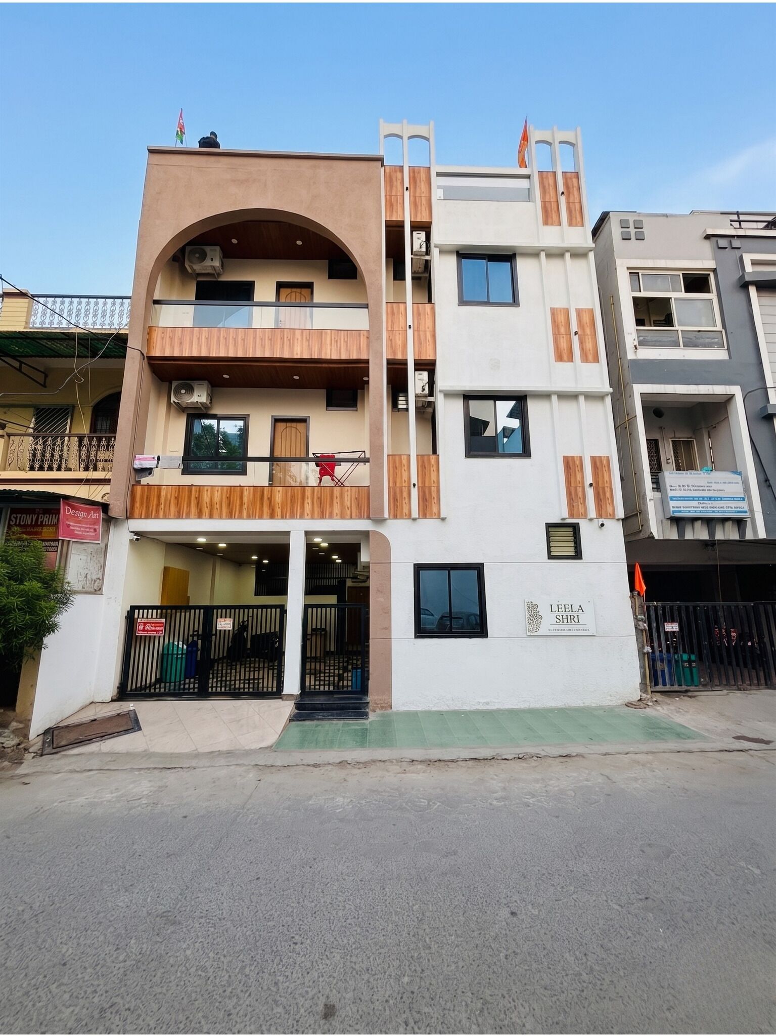 A multi-story building with a flat roof, a balcony, and a gated entrance.