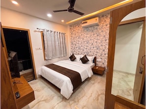 Un dormitorio con una cama, una mesita de noche, un ventilador de techo y un aire acondicionado de pared.