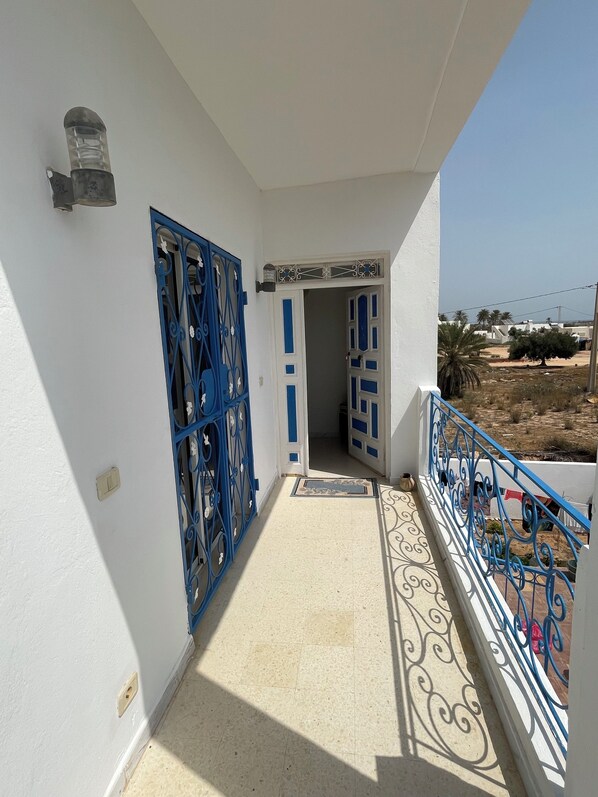 A balcony with a tiled floor and blue metal railings.