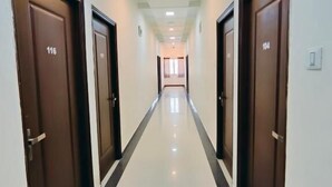 A corridor with doors numbered 116 and 104, leading to a bright room with a window.