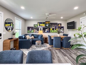 Una sala de estar moderna con un sofá, sillas, una mesa de centro y un televisor.