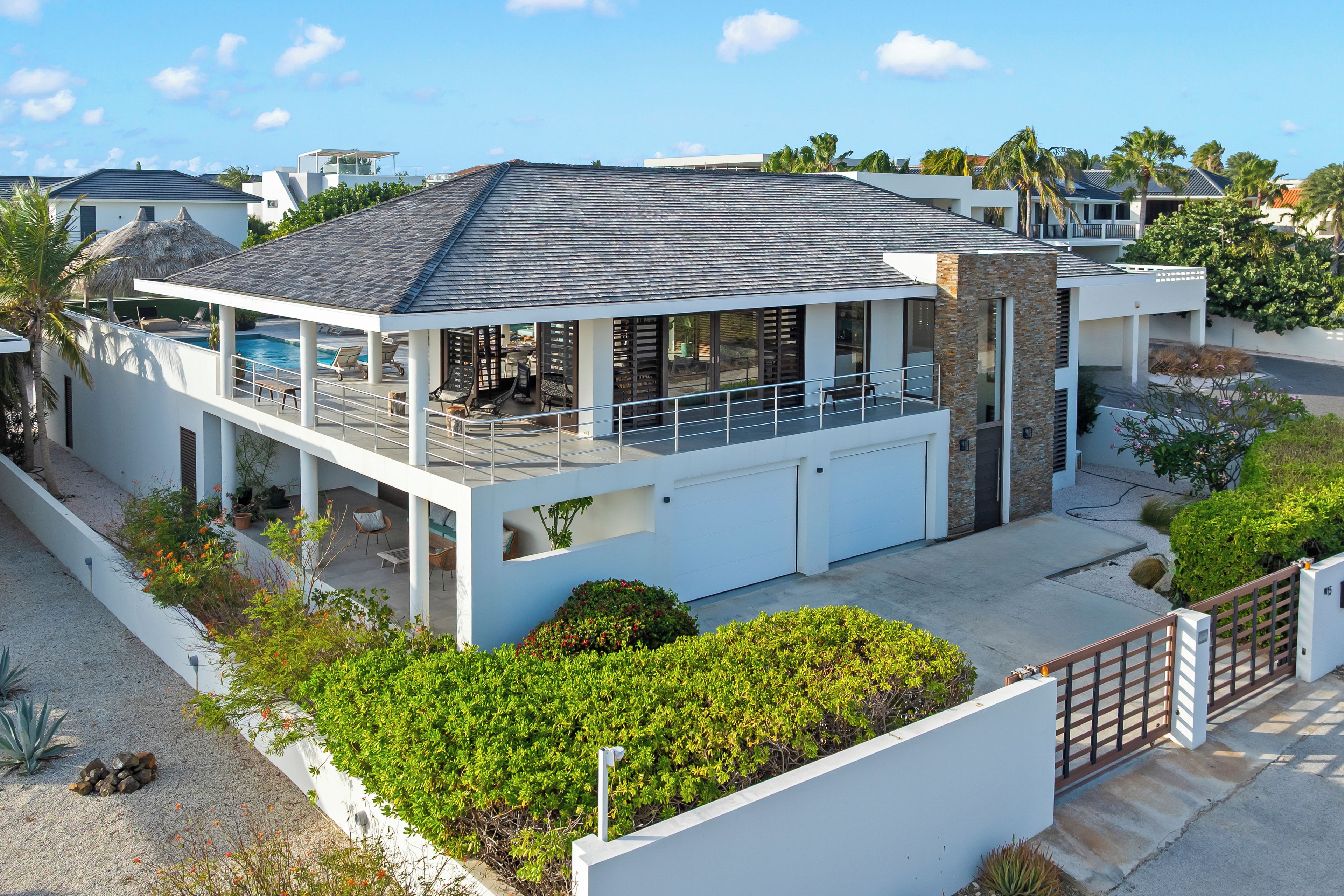 Et moderne hus i to etager med en overdækket terrasse, swimmingpool og garage.