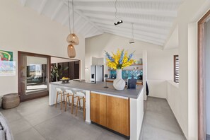 A modern kitchen with a central island, bar stools, and a decorative vase with flowers. - Villa Jan with swimming pool (Jan Thiel)