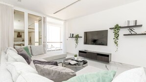 Ett modernt vardagsrum med en soffa, ett soffbord, en tv och en balkong med utsikt.