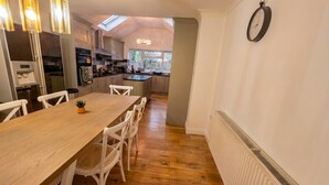 A modern kitchen with a dining area, wooden flooring, and a skylight. - Detached 5-Bed with Games Room · Quedgeley near Gloucester · Sleeps 10 (Quedgeley)