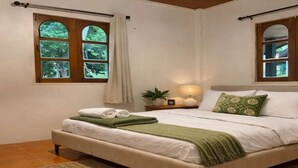 A bedroom with a bed, a nightstand, a lamp, and a window with curtains. - Tropical Home for Remote Work & Long Stays | Hin Kong (Ko Pha-ngan)