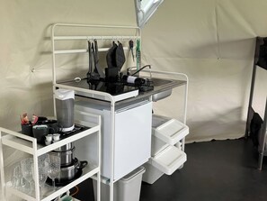 Ett litet kök med spishäll, diskho och hyllor för förvaring.