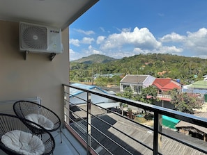 A balcony with two black wire-framed chairs and a ceiling fan. - 1BR Mountain View Apartment Rawai | CapitalPro (Rawai)