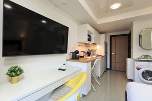 A modern kitchen with a flat-screen TV, a coffee maker, and a washing machine. - Studio Green View near Yanui Beach | CapitalPro (Rawai)