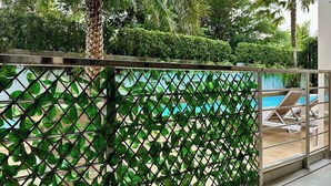 Ein Poolbereich mit Blick auf einen Pool, Liegestühle und ein Metallzaun mit Grünpflanzen.