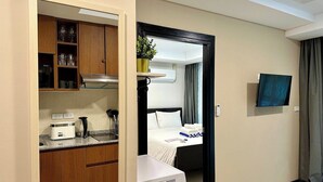 Ein Hotelzimmer mit einer Küchenzeile, einem Bett, einem Fernseher und einem Badezimmer.